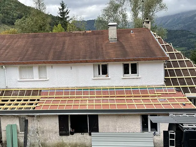 Charpente reprise et liteaux neufs ; à droite, le pan latéral en cours. Appentis refait en bac acier.